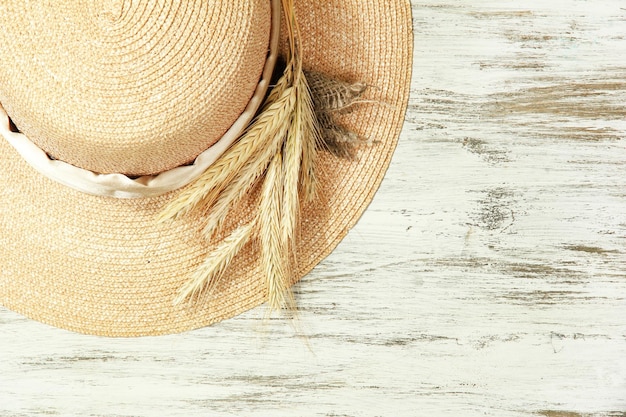 Beautiful summer hat with spikelets on wooden background