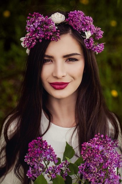 Beautiful Summer Woman with Flowers and Floral Wreath on Head Outdoor Summer Portrait of Young Smiling Model Female Face Closeup