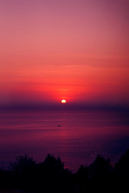 Photo the beautiful sun setting on the horizon with a view of the sea in the foreground