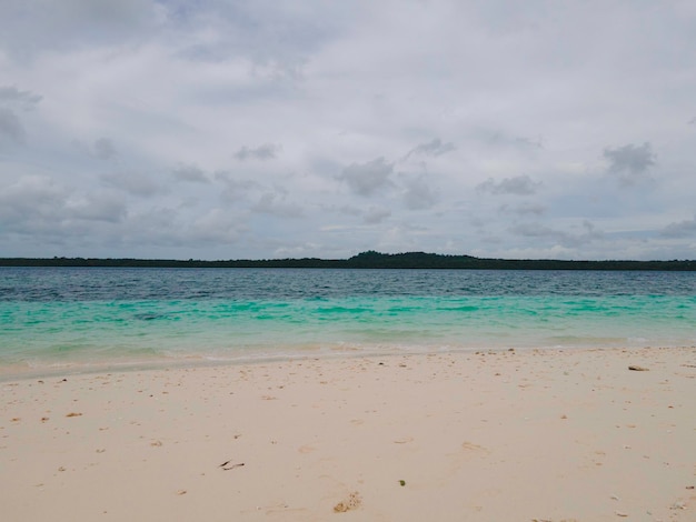 Beautiful sunny day on a calm pristine beach with grey skies in Indonesia