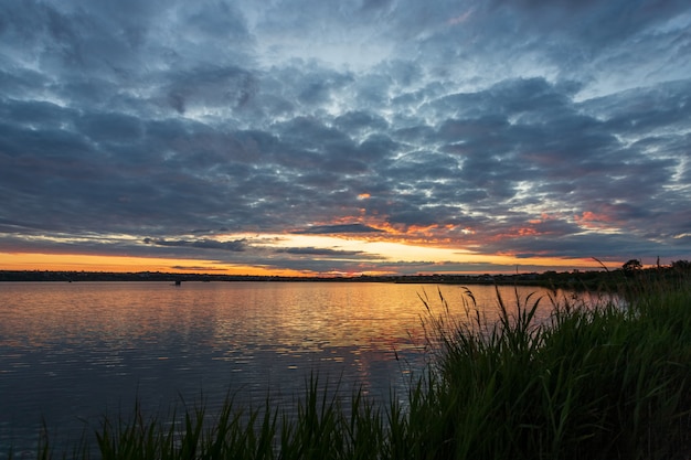 Beautiful sunrise on the river, before sunrise, with part of the shore and reeds