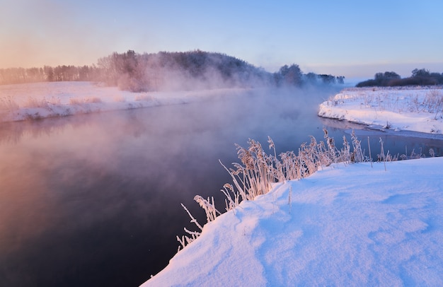 Beautiful sunrise on the river in fog in winter