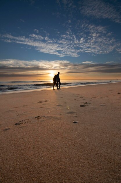 Photo a beautiful sunset on the beach of mazagon spain silhouetted by walkers on the shore