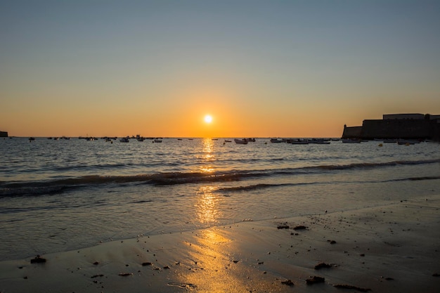 Beautiful sunset on a beach with fishing boats at the bottom Caleta beach Cadiz Spain