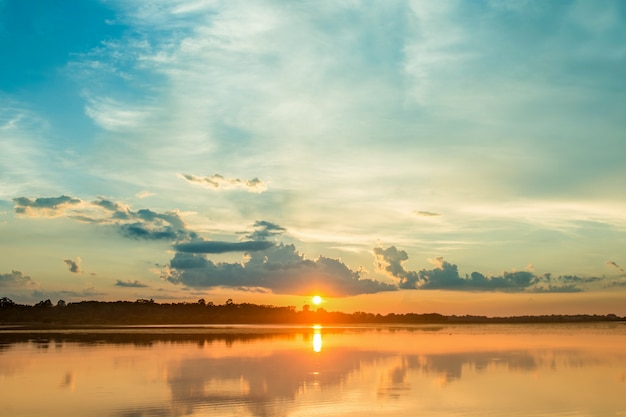 beautiful sunset behind the clouds above the over lake landscape background. 