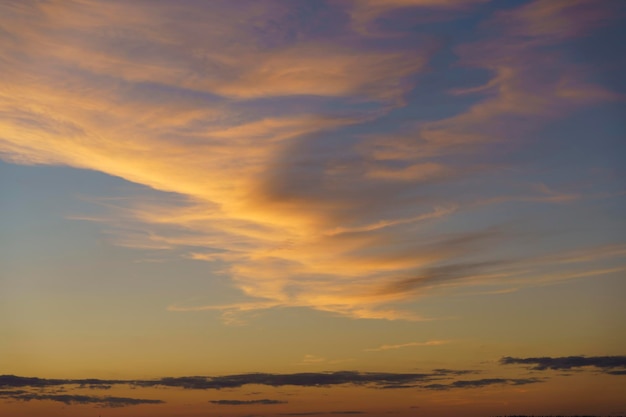 Beautiful sunset or dawn sky background with clouds of vibrant evening yellow orange colors