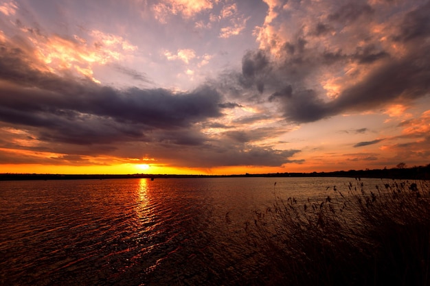 Beautiful sunset on the lake with clouds and sun rays