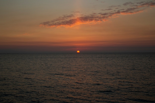 Beautiful sunset above the sea The setting sun over the ocean, in the evening, the sun sinks into the water