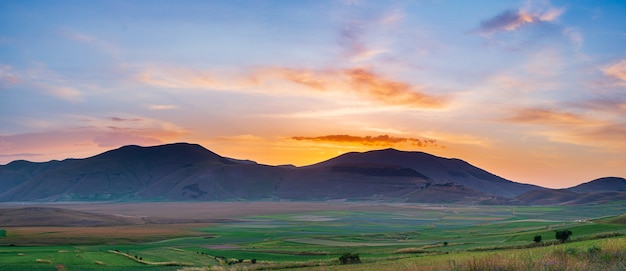 Beautiful sunset sky at Castelluccio di Norcia highlands, Italy. Blooming cultivated fields, famous colourful flowering plain in the Apennines. Agriculture of lentil crops.