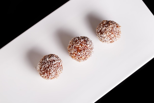 Beautiful sweets with coconut on a white plate on a black background