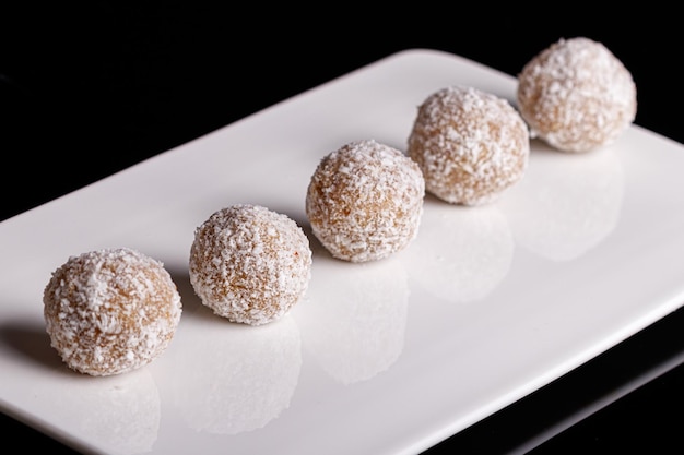 Beautiful sweets with coconut on a white plate on a black background