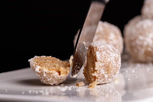 Beautiful sweets with coconut on a white plate on a black background