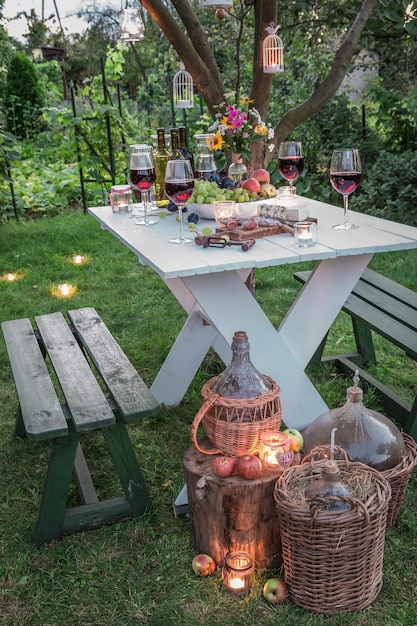 Beautiful table full of wine and fruits in garden at dusk