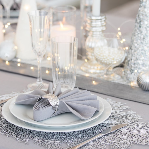 Beautiful table setting with Christmas decorations. Silver colors