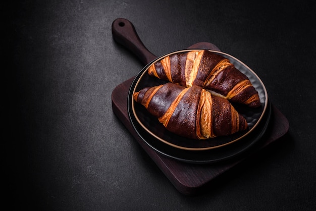 Beautiful tasty fresh crispy croissant on a dark concrete background Dessert for a delicious nutritious breakfast