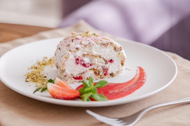 Beautiful tasty green vegan dessert pistachio strawberry rolls on a wooden table in the interior.