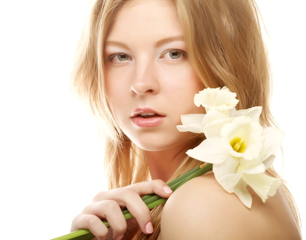 Beautiful teen girl smiling and with flower narcissus and looking at camera.