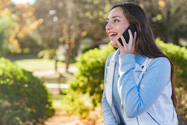 Beautiful teenage girl talking on her mobile phone in a park