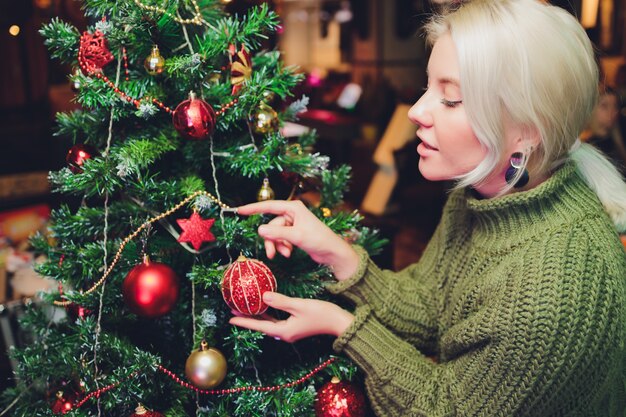 Beautiful teenager girl decorating the Christmas tree.