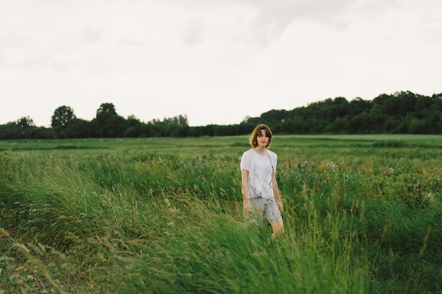 Beautiful teenager girl on the field in green grass and blowing dandelion Outdoors Enjoy Nature Healthy Smiling Girl on summer lawn Allergy free concept