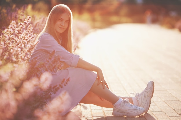 Beautiful teenager girl sitting Outdoors in flowers