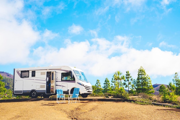 Beautiful tourism camper van campsite in the nature Travel and rv renting vehicle vacation Vanlife and wanderlust concept with modern motorhome parked in the nature with blue sky background