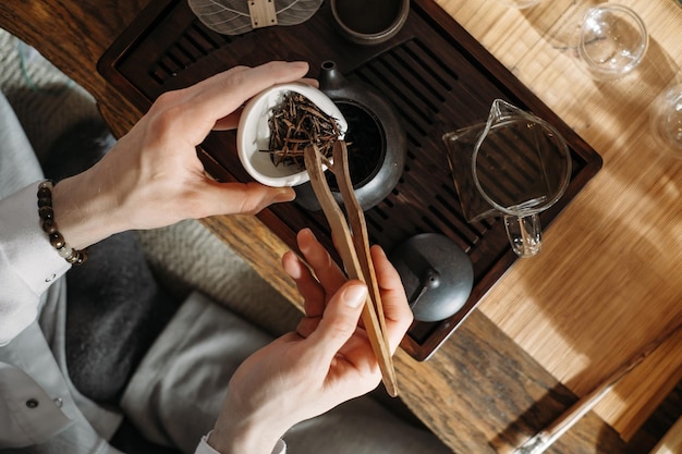 Beautiful traditional Chinese ceremony Gun Fu Cha Master pouring oolong from teapot with vapor on a dark background