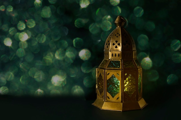 Beautiful traditional Moroccan lantern on a dark emerald background with paper fan and bokeh lights