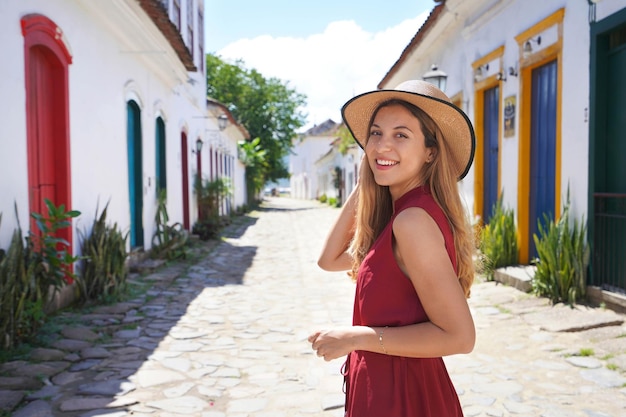 Beautiful traveler girl exploring the historic town of Paraty in Rio de Janeiro State Young tourist woman smiling at camera in Paraty village UNESCO World Heritage Site Brazil