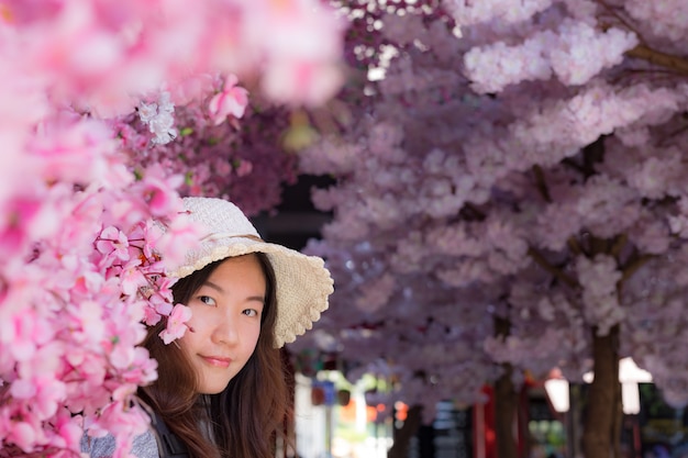 Beautiful traveler looking and touching cherry blossoms