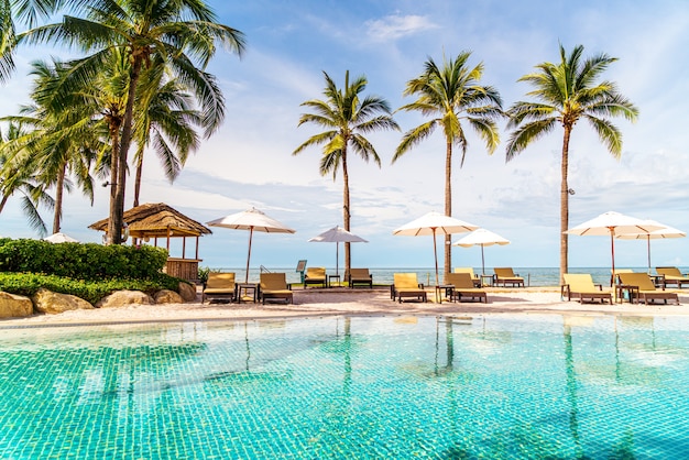 Beautiful tropical beach and sea with umbrella and chair around swimming pool in hotel resort for travel and vacation