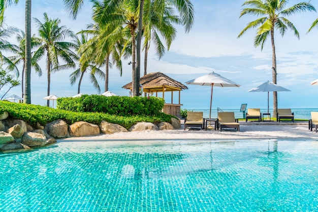 Beautiful tropical beach and sea with umbrella and chair around swimming pool in hotel resort for travel and vacation