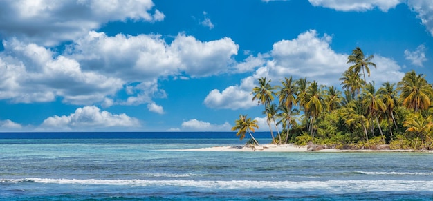 Beautiful tropical beach with white sand, palm trees, turquoise ocean against blue sky with clouds