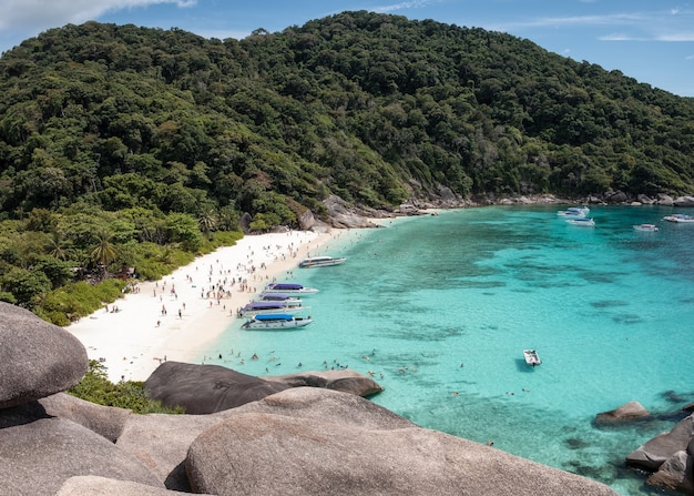 Beautiful tropical sea with stone cliff and tourists traveling by speedboat in Similan Island