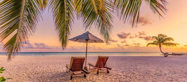 Beautiful tropical sunset beach. Romantic couple goals, two sun beds umbrella under palm tree leaves