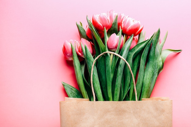 Beautiful tulips bouquet in bag on pink