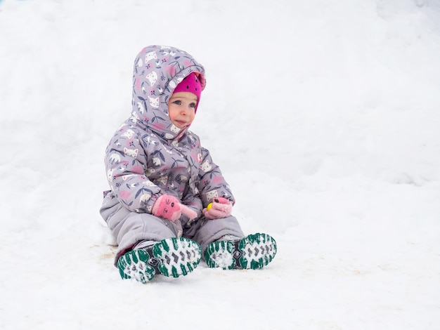 Beautiful two year old child is tired and resting in the snow copy space