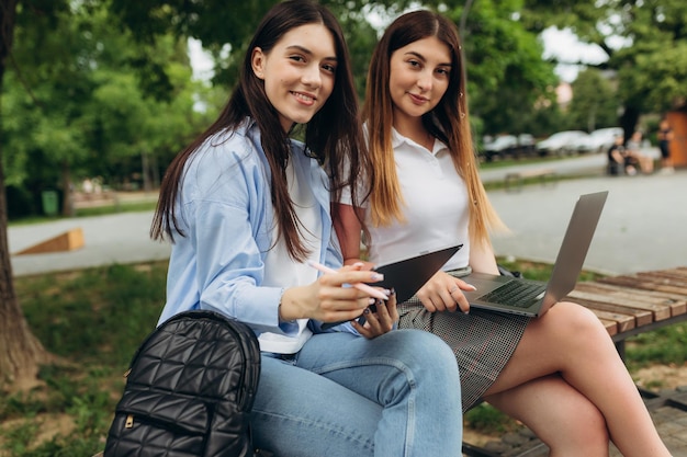 Beautiful two young girls work and study using gadgets Students use laptop and tablet