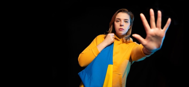 Beautiful Ukrainian girl with the national state flag of Ukraine on black background Copy space Russian Ukrainian War Help and Pray for Ukraine Stop war