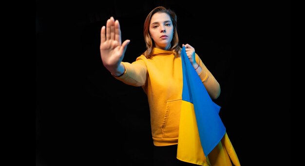 Beautiful Ukrainian girl with the national state flag of Ukraine on black background Copy space Russian Ukrainian War Help and Pray for Ukraine Stop war