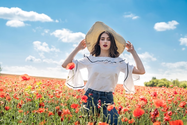 Beautiful ukrainian lady alone in straw hat  at flowers poppies field, sexy, sunny day