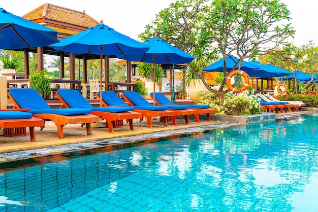 Beautiful umbrella and chair around swimming pool in hotel and resort - vacation and holiday concert