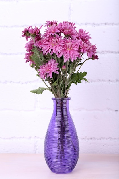 Beautiful vase with flowers on fireplace in room