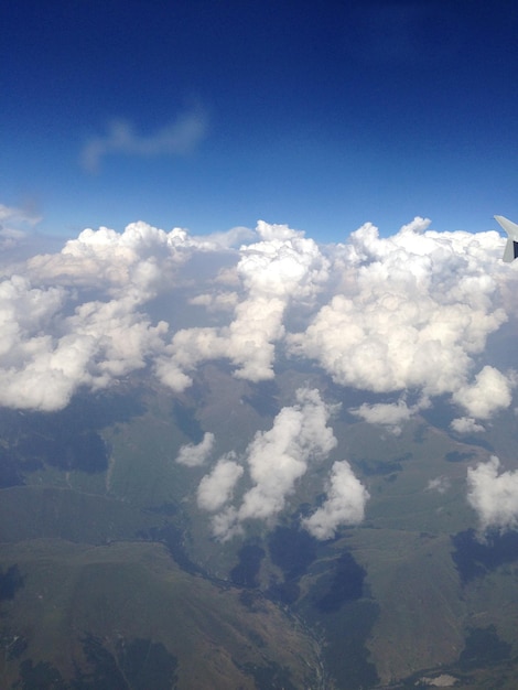 Photo beautiful view from the airplane window to the ground clouds sky small buildings rivers mountains an