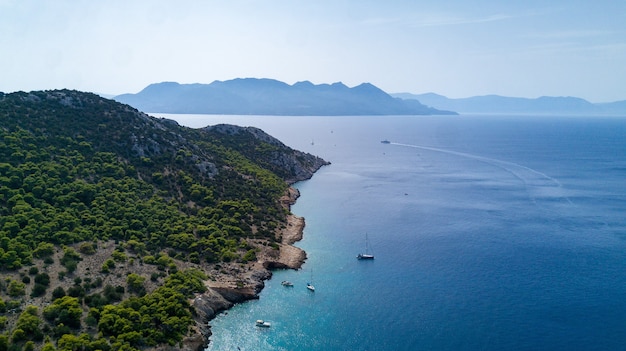 Beautiful view of green peninsula with yachts and boats near it in Greece