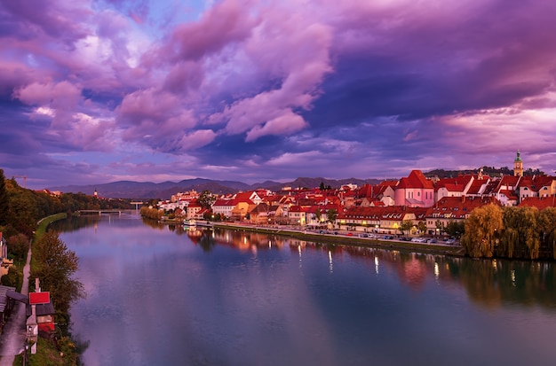 Beautiful view of Maribor city, Slovenia, at sunrise, with river and dramatic sky. Travel outdoor landscape.