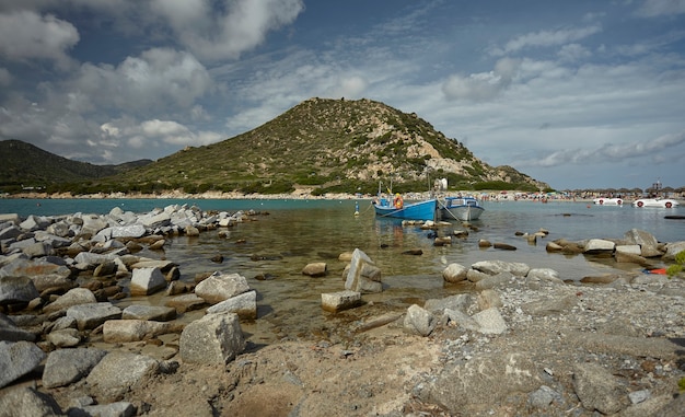 Beautiful view of Punta Molentis, a natural beach on the southern coast of Sardinia with a couple of small fishing boats moored on the shore.