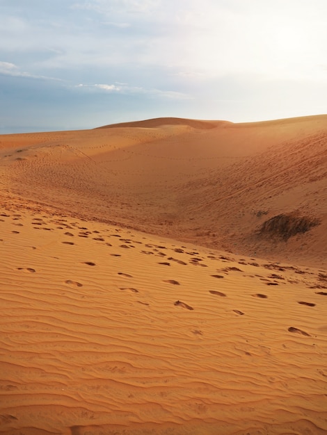 Beautiful view of red sand dunes with footprints texture background.