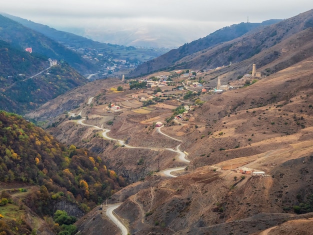 Beautiful views of Ingushetia A road across the valley Highaltitude plateau with a mountain serpentine and autumn rocky terraces High mountain valley