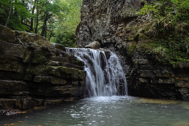 Beautiful waterfall closeup. small forest river. Streams of water fall from the rock.